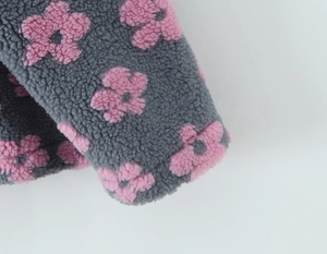 Close-up of grey sherpa fleece fabric featuring soft pink flower embroidery texture