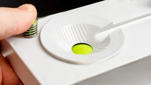 Macro shot of a finger pressing the green button on the white brush cleaner tool