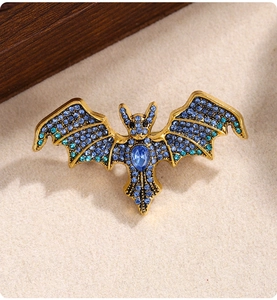Macro shot of vintage bat brooch with blue rhinestones on a beige stone surface