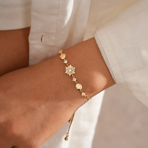 Detail of adjustable gold snowflake bracelet with sparkling zircons on a model's wrist