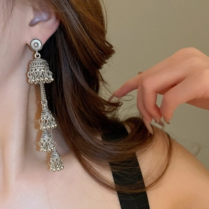 Ethnic style silver layered bell earrings with long tassels on a side profile model