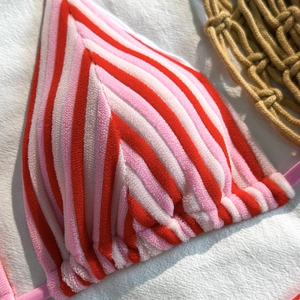 Detailed macro view of red and pink striped terry cloth bikini top with V-shaped texture