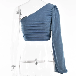 Détail du crop top bleu à une épaule et manches longues avec des détails froncés