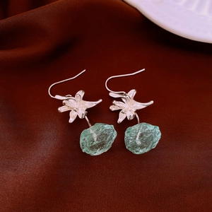 Detailed close-up of a silver flower earring with a green translucent resin drop