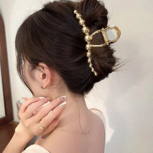 Minimalist large gold metal shark clip with beaded design on hair for elegant styling