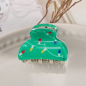 Macro detail of green acrylic hair clip featuring festive string light patterns and metal teeth