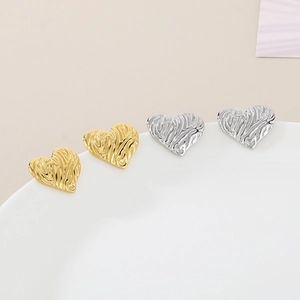 Dettaglio ravvicinato degli orecchini a cuore con texture ondulata in oro e argento