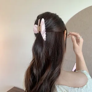 Detailed view of a pink butterfly acetate hair claw clip on dark brown wavy hair