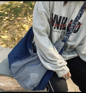 Detail of blue denim patchwork tote bag with braided shoulder strap and spacious interior