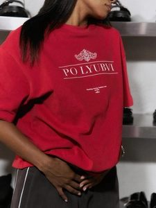 Detailansicht des weißen Buchstabendrucks auf einem roten Oversize Baumwoll T-Shirt