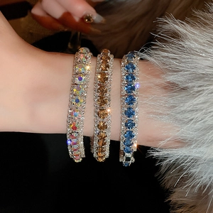 Close-up of three wide luxury bracelets with rainbow, gold, and blue rhinestones