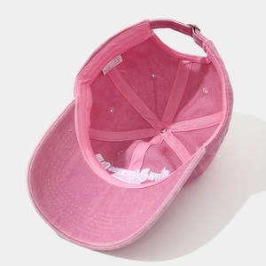 Detail of pink washed cotton baseball cap showing 100% cotton label and metal buckle