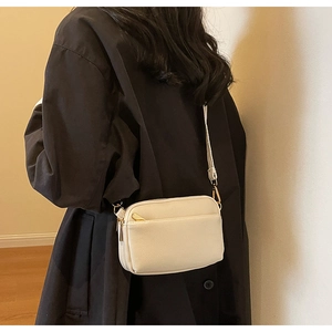 Close-up of cream crossbody bag in textured PU leather with golden hardware accents