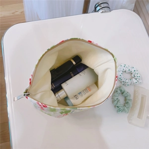 Top view of large capacity floral cotton makeup bag filled with various skincare products