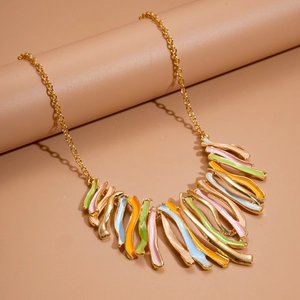 Macro shot of colorful enamel geometric fringe pendants on a delicate gold chain necklace