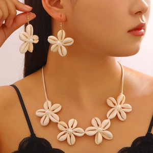 Dettaglio di collana a fiori di conchiglia e orecchini di perle per vacanze al mare