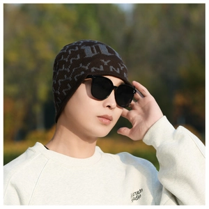 Close-up of brown knit beanie with grey patterns and large black sunglasses for winter