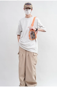 Detail view of a transparent PVC crossbody bag with orange trim worn by a model