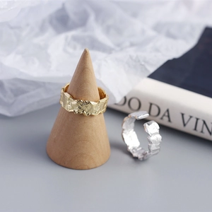 Macro detail of gold and silver irregular hammered texture rings on artistic backdrop