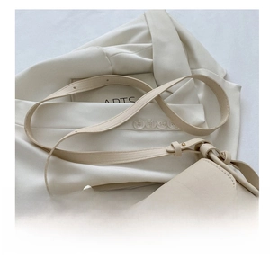 Detail of adjustable shoulder strap and gold hardware on beige handbag with scarf