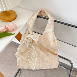 Detail of floral embroidery and white lace bow decoration on cream tote bag