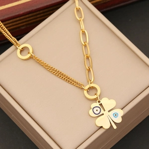 Detail of gold double-layer chain necklace featuring a clover pendant with eye patterns