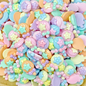 Close-up of pastel resin charms including stars and lollipops for DIY nail art and jewelry