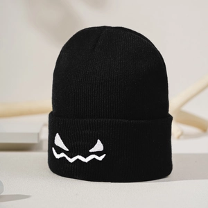 Close-up of black ribbed knit beanie featuring white embroidered funny pumpkin face