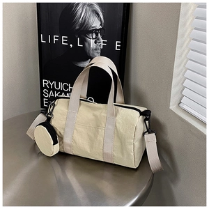 Detail showing beige cylindrical handbag with a round mini coin purse on a metal surface