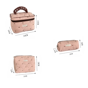 Detailed view of three-piece pink quilted makeup bags with strawberry bow embroidery