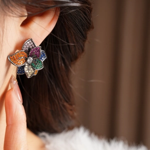 Close-up of vintage floral stud earrings with multi-colored cubic zirconia on female model
