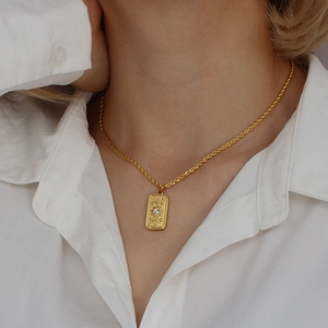Gold tarot sun pendant necklace with star patterns and zircon on a model in white shirt