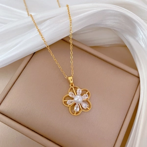 Detail of gold necklace with pearl flower pendant and zircon stones on silk fabric