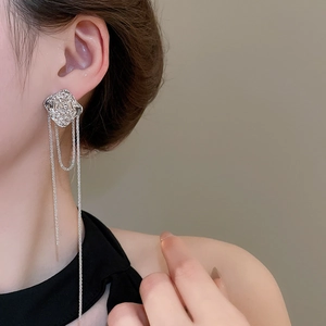 Close-up of silver long tassel earrings with irregular textured rose flower studs