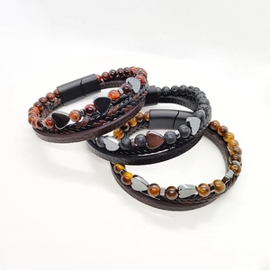 Dettaglio di bracciali multistrato in pelle intrecciata con perline a cuore e chiusura
