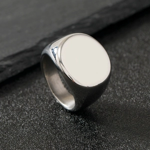 Close-up of a silver polished stainless steel geometric ring on a dark rock surface