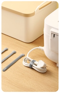 Detail shot of grey nylon cable tie organizing power cords on a wooden desk surface
