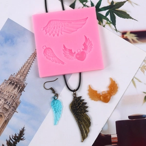 Detail of pink silicone mold for wings and heart charms with finished resin crafts