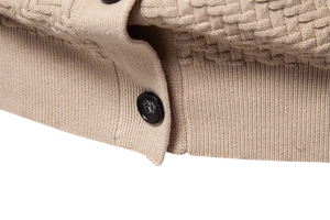Macro view of beige knit cardigan showing detailed texture and black resin buttons