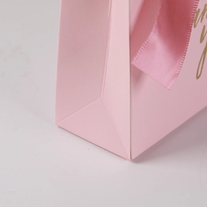 Close-up of pink wedding gift bag with gold foil Thank You text and silk ribbon handle