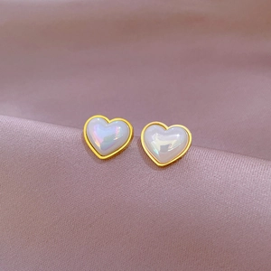 Minimalist titanium steel heart stud earrings with iridescent finish on pink silk background