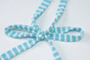 Detail of blue and white striped knit drawstring tied in a bow on summer outfit
