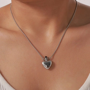 Minimalist silver heart pendant necklace on model featuring a sleek snake chain