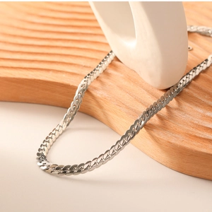 Macro shot of polished silver stainless steel flat snake chain on a wooden tray