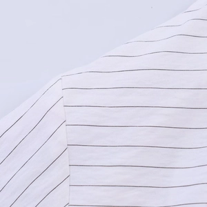 Close-up of black and white striped shirt fabric showing precise shoulder seam stitching