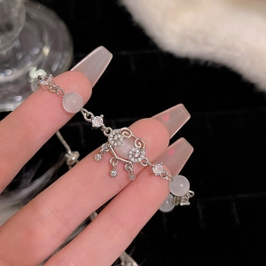 Macro view of silver bracelet featuring a cat eye stone and Ruyi peace lock on wrist