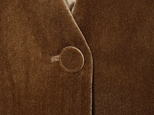 Vue détaillée de la texture velours bronze et du bouton rond recouvert de tissu assorti