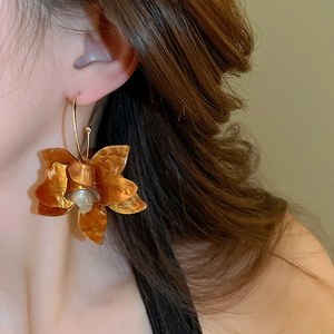Detail of amber resin flower earring with pearl center worn by a female model