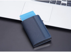 Blue RFID PU leather pop-up card holder shown next to a laptop on a black desk