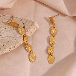 Détail de boucles d'oreilles ovales dorées martelées sur soie et pierre décorative